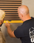 Twee mannen meten een muur.